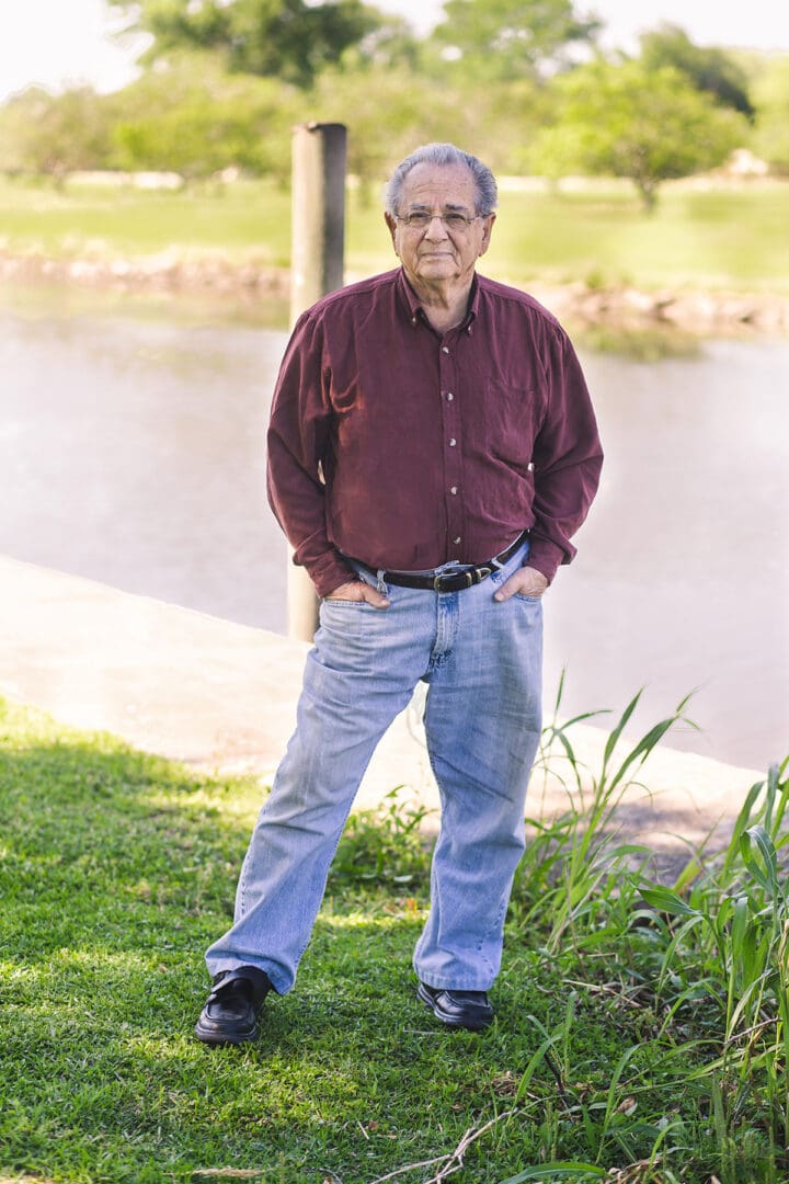 A man standing in the grass near water.